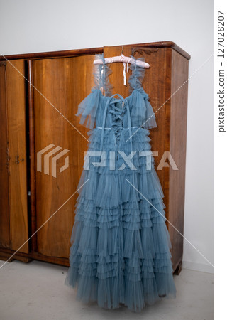 Elegant Blue Tulle Dress Hanging on Wooden Wardrobe 127028207