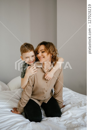 Joyful Family Moment: Child Hugging Parent on Bed 127028219