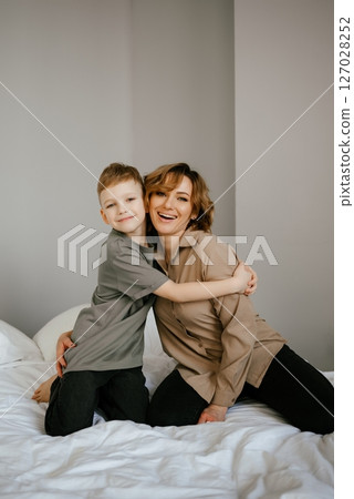 Mother and Son Embracing on Bed, Smiling Together Mother and Son Embracing on Bed, Smiling Together 127028252