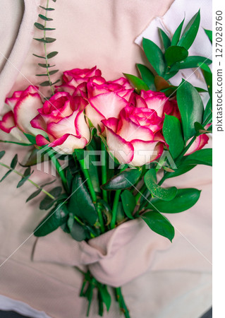 A bouquet of roses is wrapped in a coarse knit woolen sweater. A bouquet of roses is wrapped in a coarse knit woolen sweater. 127028760