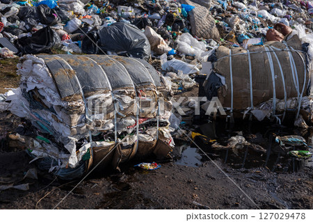 Debris and waste piled high at a landfill with compressed bales, emphasizing the urgency of proper waste disposal and environmental care 127029478