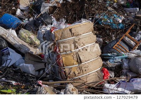 Piles of waste, including cardboard and plastic, are stacked haphazardly in an urban location, highlighting pollution issues 127029479