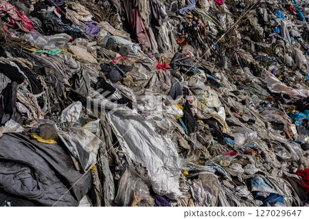 A sprawling landfill showcases a mixture of brightly colored fabrics and plastics piling up, highlighting ongoing pollution issues in the ecosystem 127029647