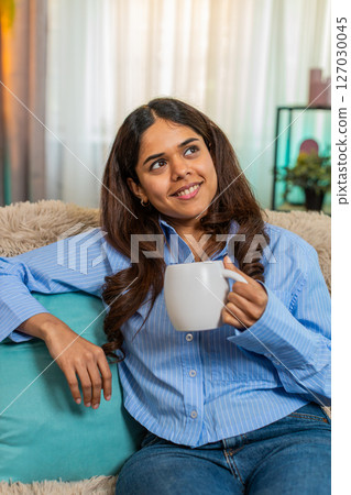 Indian woman drinking tea with peaceful face at home enjoying calm personal moment of relaxation Indian woman drinking tea with peaceful face at home enjoying calm personal moment of relaxation 127030045