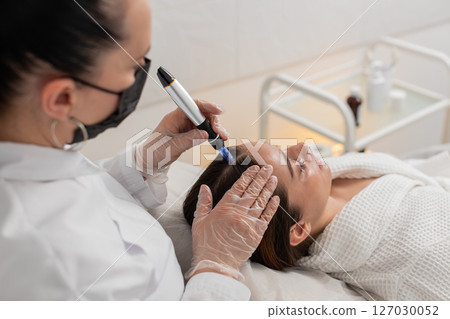 Woman receives microneedling and injections for hair growth scalp therapy in trichology clinic 127030052