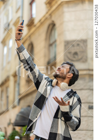 Young male tourist trying to catch communication signal and Internet on smartphone in city street 127030438