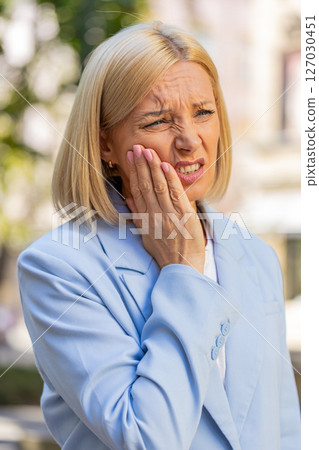 Mature Caucasian businesswoman feeling toothache bad unpleasant symptoms suffering from pain outdoor Mature Caucasian businesswoman feeling toothache bad unpleasant symptoms suffering from pain outdoor 127030451