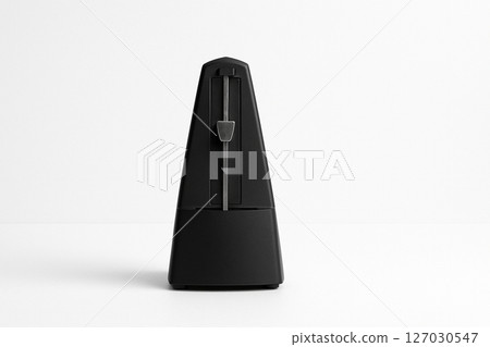 A simple black metronome placed on a white background 127030547