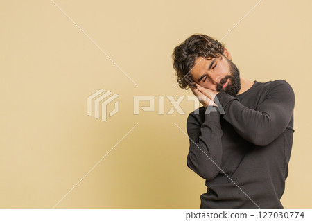 Tired overworked man yawning sleepy feeling bored suffering from lack of sleep on beige background 127030774