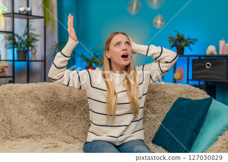 Caucasian woman irritated by noisy neighbors covering ears on sofa construction music loud indoors Caucasian woman irritated by noisy neighbors covering ears on sofa construction music loud indoors 127030829