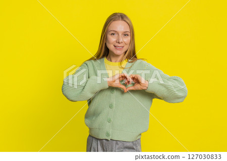 Smiling young woman makes heart gesture demonstrates love sign expresses good feelings and sympathy 127030833