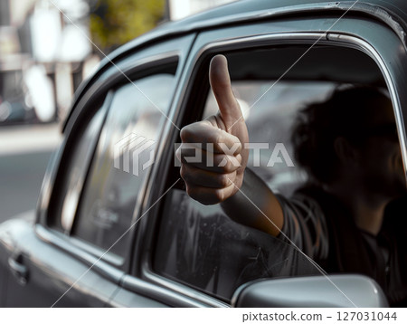 A hand with a thumbs-up gesture is extended out of a car window. Concept of approval and positivity. 127031044