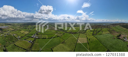 Aerial view on rural landscape in Ireland, Green grass fields divided by traditional dry stone fences. Aerial view on rural landscape in Ireland, Green grass fields divided by traditional dry stone fences. 127031388