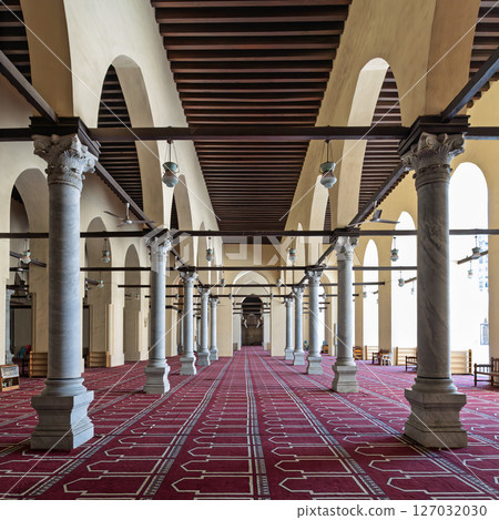 Historic mosque of al-Zahir Baybars features intricate columns and a vibrant prayer carpet in Cairo, Egypt 127032030