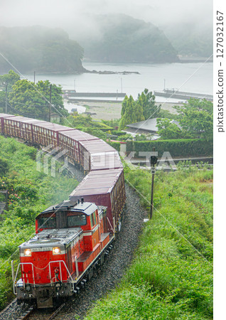 一輛柴油火車在大雨中沿著太平洋行駛在紀勢本線上。 一輛柴油火車在大雨中沿著太平洋行駛在紀勢本線上。 127032167