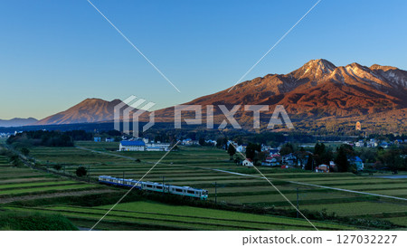 Mt. Myoko shining in the morning glow and the local train running along its base 127032227
