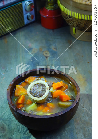 A rich bone marrow soup with chunks of carrots and meat, served in a rustic wooden bowl. A rich bone marrow soup with chunks of carrots and meat, served in a rustic wooden bowl. 127033557