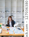 Successful young businesswoman works with graphs at her bright office desk. 127036380