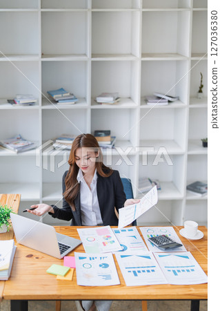Successful young businesswoman works with graphs at her bright office desk. Successful young businesswoman works with graphs at her bright office desk. 127036380