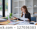 Young business woman analyzes financial reports at her office workplace. 127036383