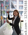 An asian businesswoman uses sticky notes on glass in a modern office space. 127036388