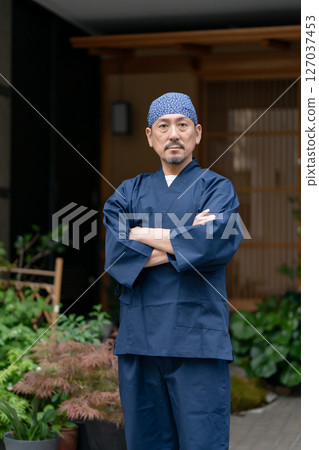 A man wearing a work uniform with his arms crossed A man wearing a work uniform with his arms crossed 127037453