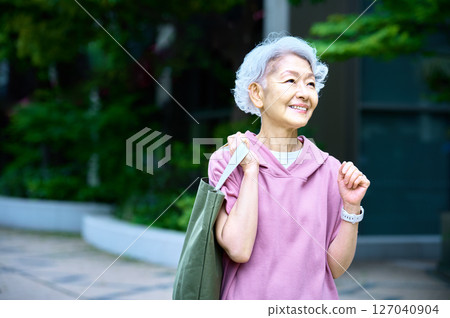 Cheerful senior woman holding a shopping bag Cheerful senior woman holding a shopping bag 127040904