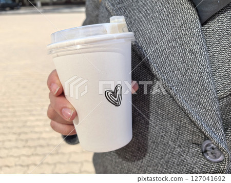Warm drink in hand on a brisk day in a bustling urban setting 127041692