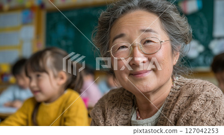 Chinese grandmother enjoys parent-teacher meeting in vibrant classroom setting 127042253