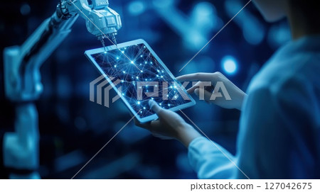 Robotic arm interacting with digital tablet in factory setting 127042675