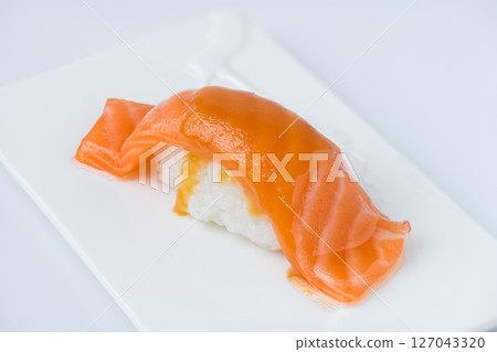 Fresh Salmon Nigiri Sushi Drizzled with Savory Sauce on Minimalist Plate 127043320