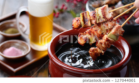 A sizzling Japanese-style cut of yakitori dipped in a secret sauce pot A sizzling Japanese-style cut of yakitori dipped in a secret sauce pot 127044001