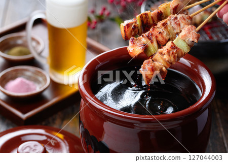 A sizzling Japanese-style cut of yakitori dipped in a secret sauce pot A sizzling Japanese-style cut of yakitori dipped in a secret sauce pot 127044003