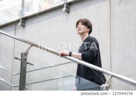一名男子站在混凝土牆旁的樓梯上，抬頭仰望 127044156