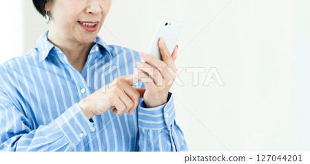 A middle-aged woman who operates a smartphone 127044201