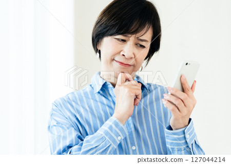 A middle-aged woman who operates a smartphone A middle-aged woman who operates a smartphone 127044214