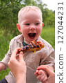 Happy toddler excited about grilled chicken at picnic 127044231