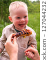 Happy toddler excited about grilled chicken at picnic 127044232