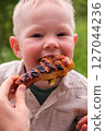 Happy toddler excited about grilled chicken at picnic 127044236