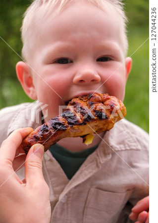 Happy toddler excited about grilled chicken at picnic Happy toddler excited about grilled chicken at picnic 127044236