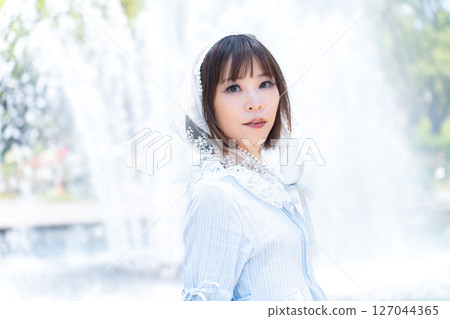 A woman in Lolita fashion in front of a fountain A woman in Lolita fashion in front of a fountain 127044365