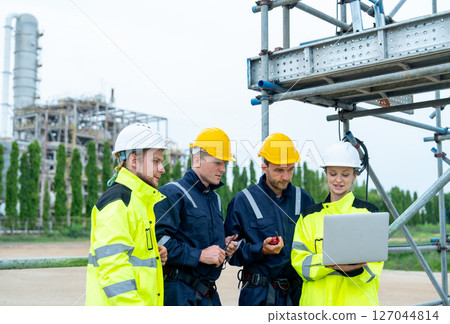 Group of petrochemical workers or technicians work together with one hold laptop and they stand in front the factory and look happiness in workplace. Group of petrochemical workers or technicians work together with one hold laptop and they stand in front the factory and look happiness in workplace. 127044814