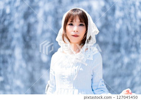 A woman in classical lolita fashion standing in front of a waterfall A woman in classical lolita fashion standing in front of a waterfall 127045450