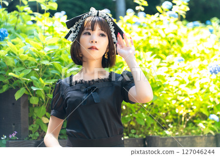 A woman in Gothic Lolita fashion standing in front of hydrangeas 127046244