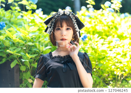 A woman in Gothic Lolita fashion standing in front of hydrangeas A woman in Gothic Lolita fashion standing in front of hydrangeas 127046245