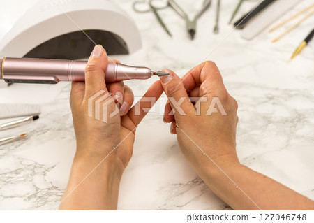 Nail drill bit closeup, woman making her gel nail manicure at home  127046748