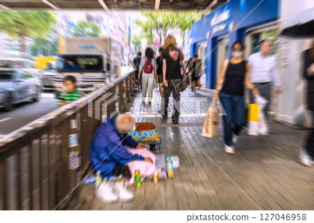 Tokyo cityscape in Japan: Elderly people smoking cigarettes... Under the overpass in front of Shibuya Scramble Crossing... Sitting on a narrow sidewalk... 127046958