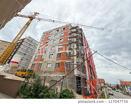Urban construction site with residential building, scaffolding, and crane. Modern development area with equipment and infrastructure installation Urban construction site with residential building, scaffolding, and crane. Modern development area with equipment and infrastructure installation 127047738