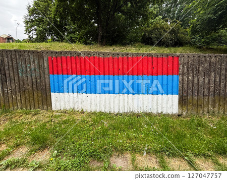 Painted Serbian flag on concrete wall in a public park. Patriotic urban art expressing national identity in everyday surroundings. Painted Serbian flag on concrete wall in a public park. Patriotic urban art expressing national identity in everyday surroundings. 127047757