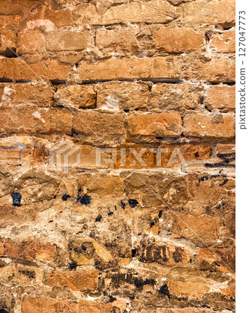 Weathered red brick wall with vintage patina and grunge texture. Warm tones and aged surface enhance the industrial style atmosphere 127047773